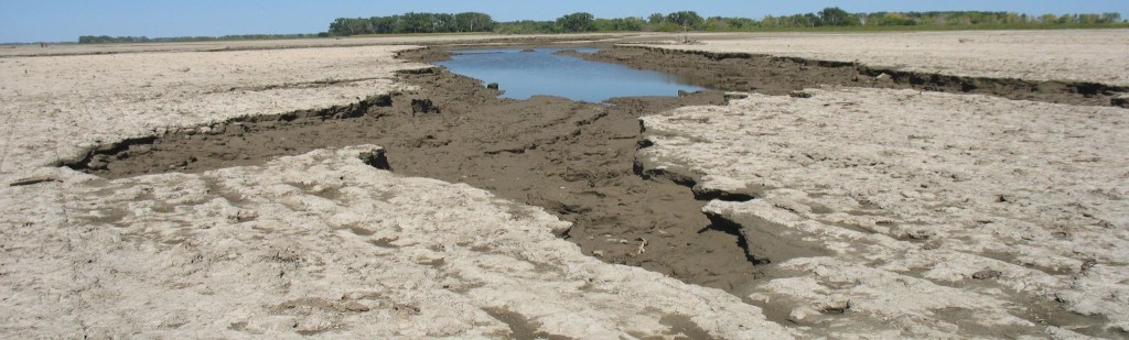flooded farm field showing erosion and body of water in soil